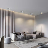 Directional ceiling lights washing a curtained living room wall above a sofa