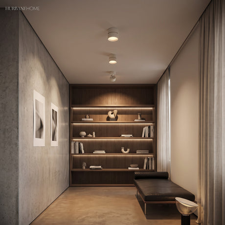Warm ceiling spot lights over a corridor of built in shelving and framed prints
