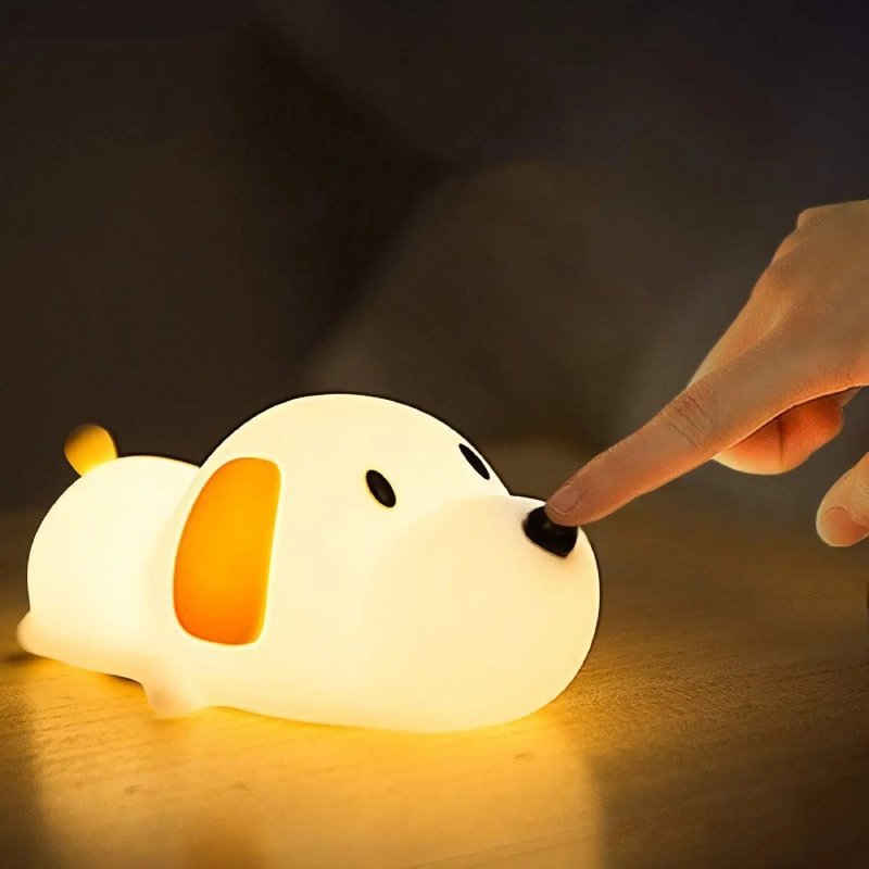 Finger tapping a dog silicone night light glowing warm on a wooden surface