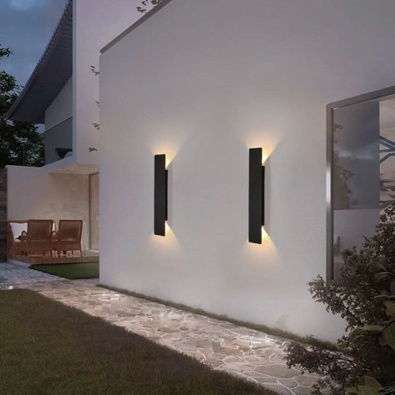 Pair of black wall sconces casting warm up and down light on a white wall