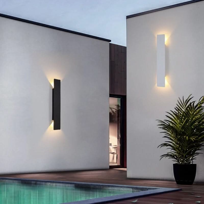Slim black outdoor LED wall light glowing on a rendered garden wall