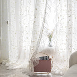 Embroidered floral tulle curtains filtering daylight in bedroom