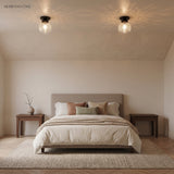 Pair of glass globe ceiling lights with black canopies above a bed