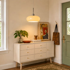 White glowing glass pendant light above an entryway sideboard