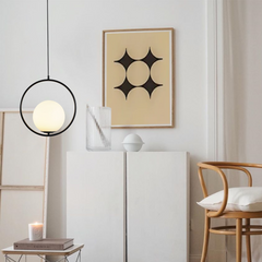 Gold oval frame glass globe pendant glowing above a bedside table with flowers
