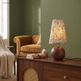 Vintage floral table lamp on a walnut sideboard against a deep green wall