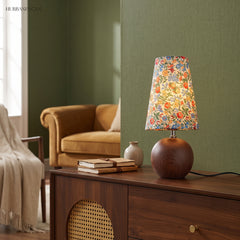 Vintage floral table lamp on a walnut sideboard against a deep green wall