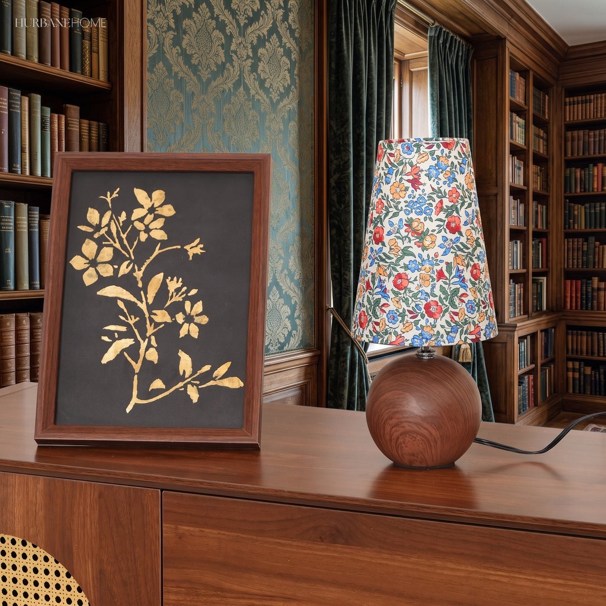 Wood base floral lamp beside a framed botanical print in a panelled library
