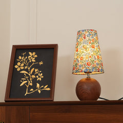 Floral table lamp glowing on a walnut sideboard in a panelled room