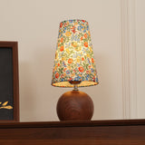 Floral table lamp lit low, showing the bulb glow through the fabric shade