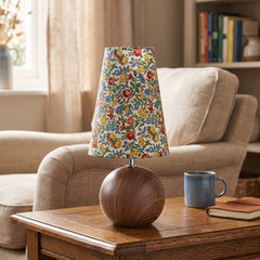 Floral shade table lamp with a round walnut base on a polished wood table