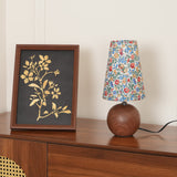 Floral table lamp and framed botanical print on a walnut cabinet