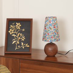 Floral table lamp and framed botanical print on a walnut cabinet