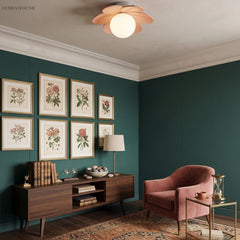 Flower ceiling light on a white ceiling in a dark green room hung with botanical prints