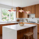 Three pink flower shaped glass pendants over a white marble kitchen island