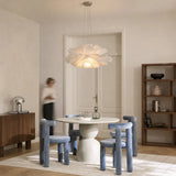 White flower pendant light above a dining room with blue chairs