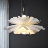 White petal flower pendant light lit against a dark grey wall