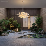 White lotus petal pendant light above a bench by a courtyard garden