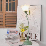 Flower table lamp beside a glass vase of yellow flowers and stacked books