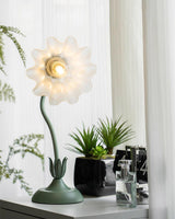 Front view of the flower shade with petals fully open around the lit bulb