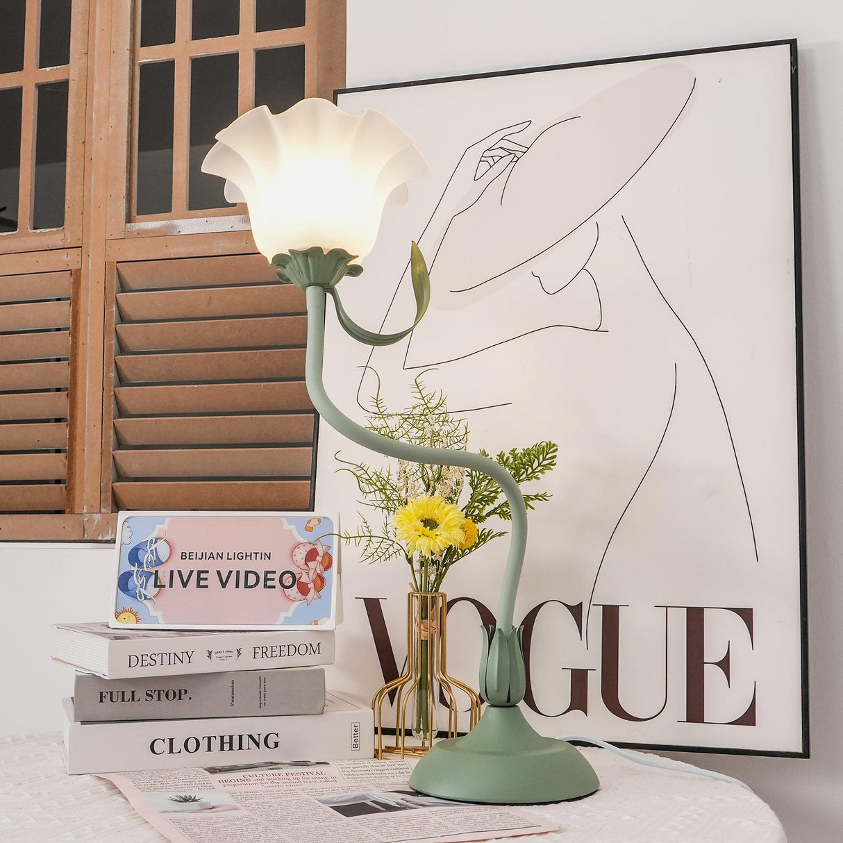 Flower table lamp lit near a wooden shutter window with a flower vase