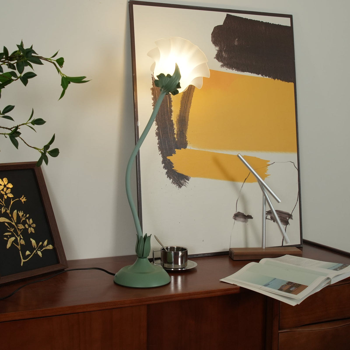 Flower table lamp on a wooden sideboard in front of a large abstract print