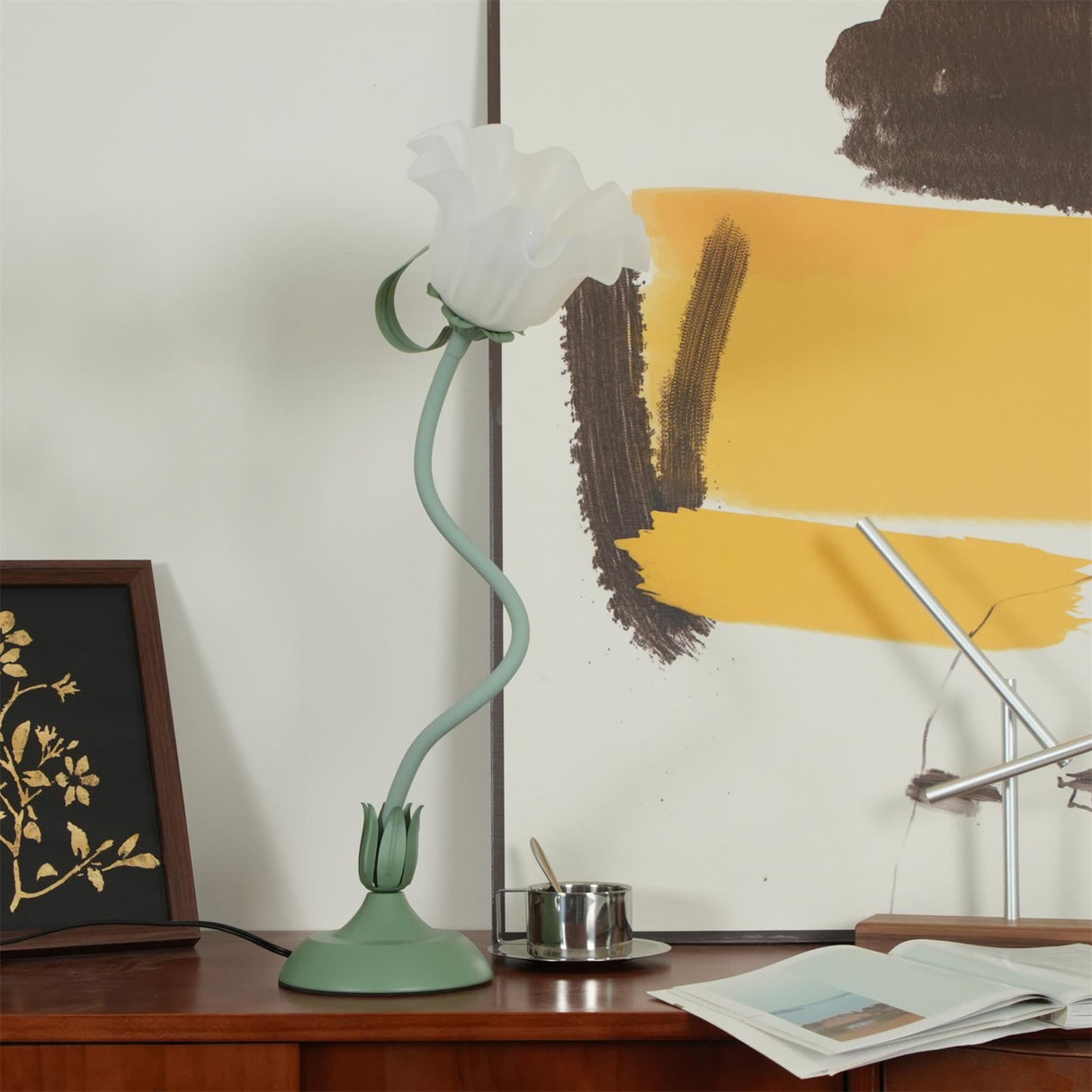 Side angle of the flower table lamp on a sideboard with artwork behind it