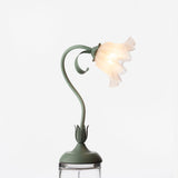 Studio shot of the lit flower table lamp raised on a clear glass plinth
