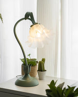 Flower table lamp glowing on a white sill beside potted succulents and a cactus
