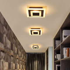 Three square coffee ceiling lights over a stone tiled corridor