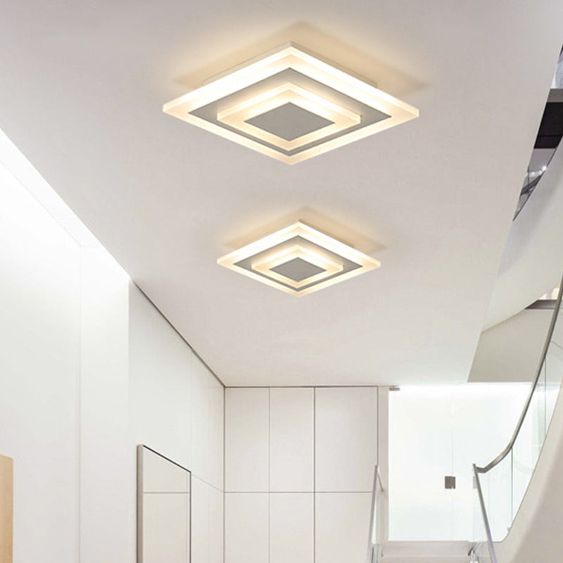Square and round white ceiling lights in a tiled hallway