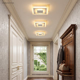 Three small square ceiling lights lining a paneled entry hallway