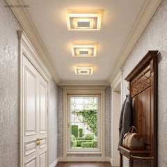 Three small square ceiling lights lining a paneled entry hallway