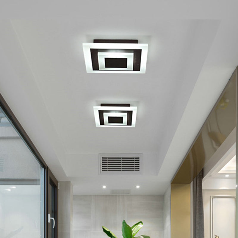 Two square ceiling lights on the ceiling of a wide bright corridor