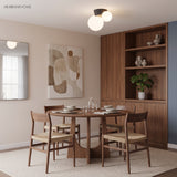 Twin globe ceiling light above a round dining table with cane backed chairs