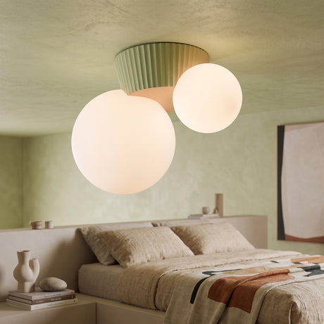Green fluted canopy ceiling light holding two opal glass globes above a bed