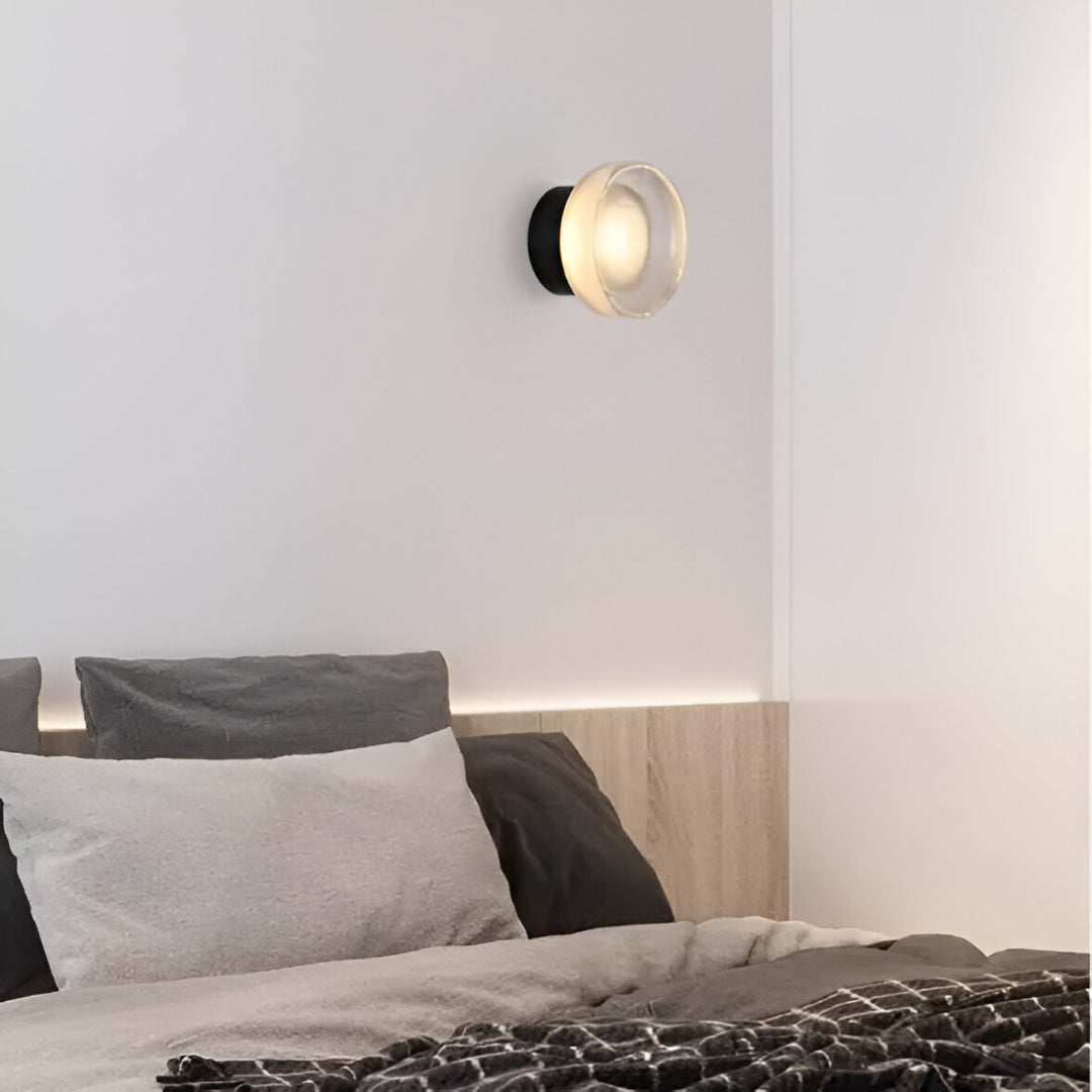 Ribbed acrylic wall light lit above a bed with grey linen