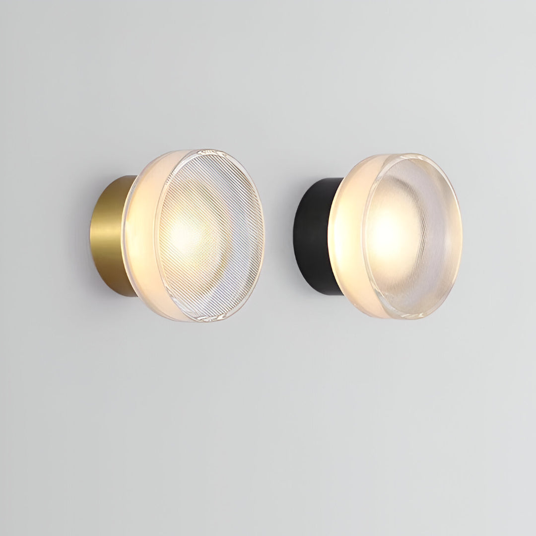 Black ribbed disc wall light lit on a pale grey wall