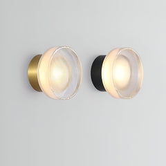 Black ribbed disc wall light lit on a pale grey wall