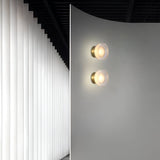 Gold ribbed wall light lit beside a sheepskin covered chair