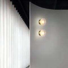 Gold ribbed wall light lit beside a sheepskin covered chair