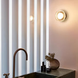 Gold ribbed wall light lit above a bedside table with a diffuser
