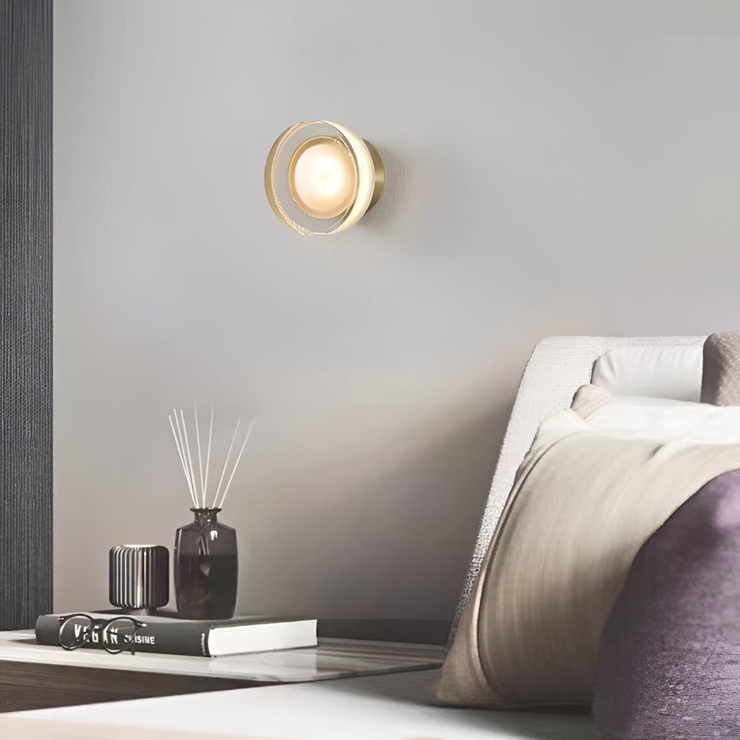 Black ribbed wall light lit above a bedside table with books