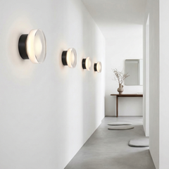 Gold ribbed wall light lit above a desk with a laptop and plant