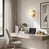 Gold ribbed wall light lit beside a window with a potted plant