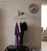 Silver ripple disc light on a wall behind a hanging clothes rail
