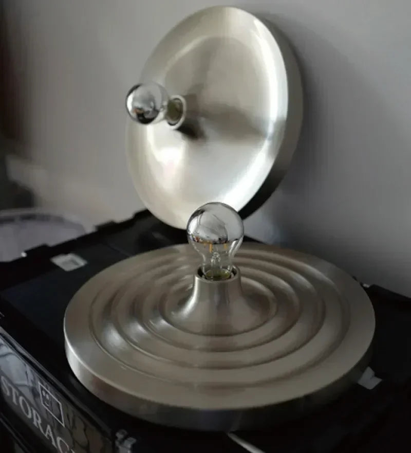 Silver disc light lit warm in a dark room above a crate