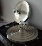 Silver disc light lit warm in a dark room above a crate