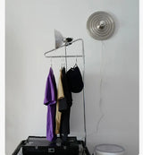 Silver ripple disc light beside a garment rail on a white wall