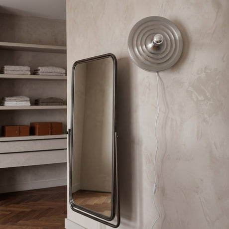 Silver ripple disc light mounted beside a clothes rail